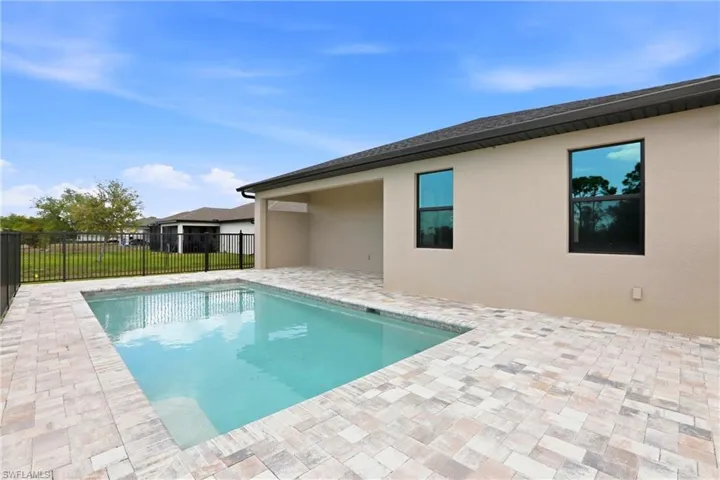 Outdoor swimming pool with surrounding paver patio and covered lanai
