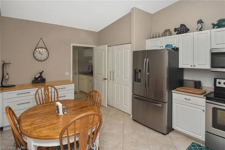 Kitchen featuring wood counters, appliances with stainless steel finishes, backsplash, light tile patterned floors, and white cabinets