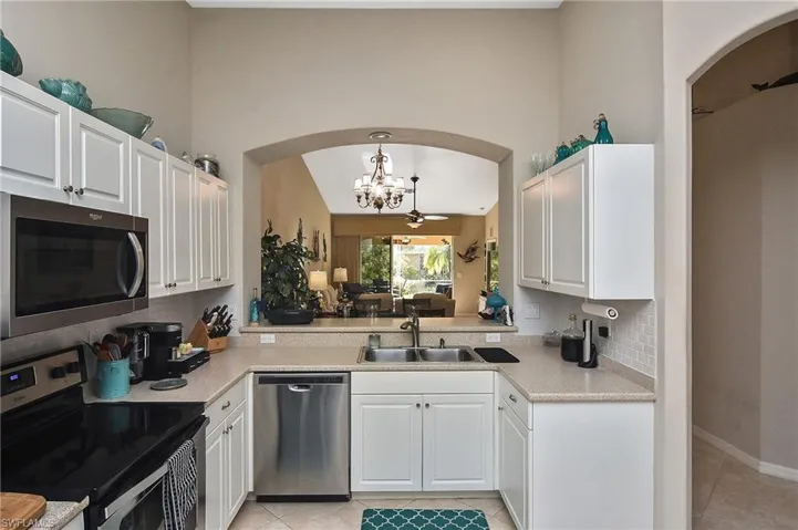 Kitchen featuring appliances with stainless steel finishes, sink, decorative light fixtures, an inviting chandelier, and white cabinetry