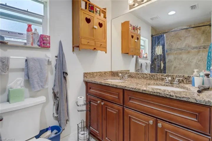 Bathroom featuring double sink vanity, toilet, and plenty of natural light