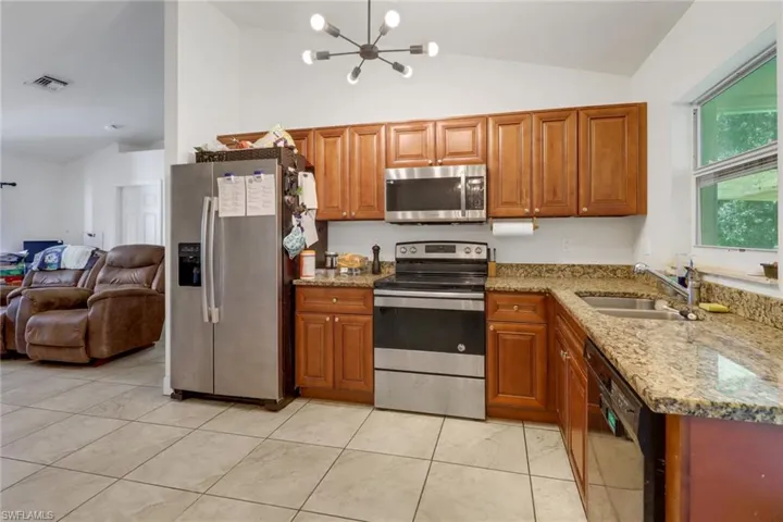 Kitchen featuring light stone counters, sink, a chandelier, and stainless steel appliances