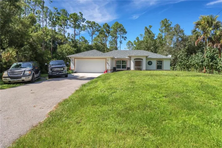 Single story home with a garage and a front lawn