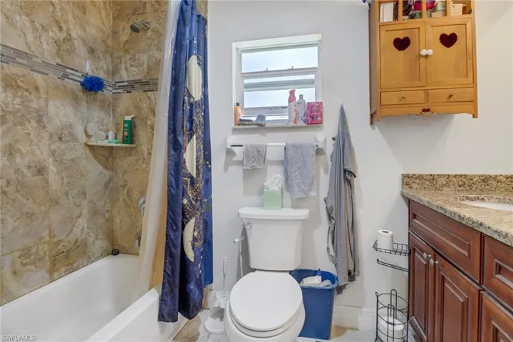 Full bathroom with shower / bath combo with shower curtain, vanity, and toilet