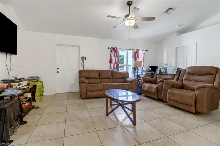 Tiled living room with lofted ceiling and ceiling fan