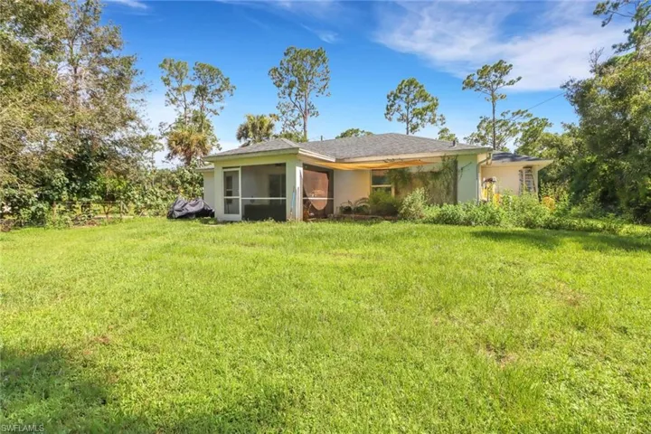 Back of property with a lawn and covered lanai