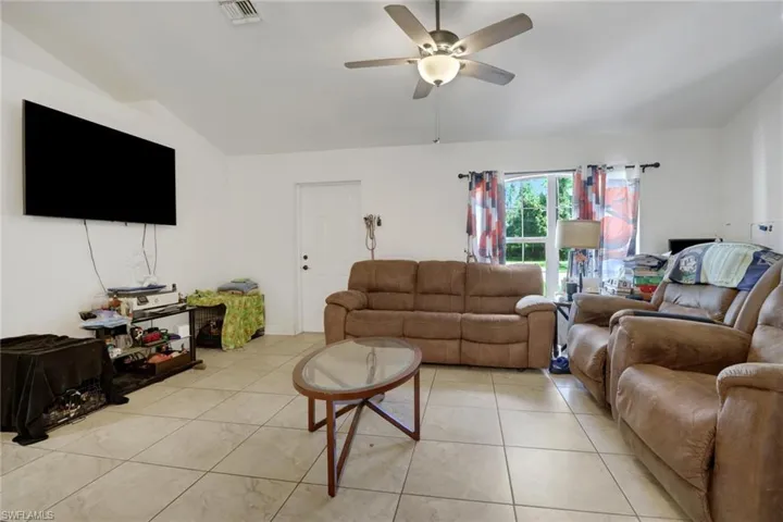 Tiled living room with vaulted ceiling and ceiling fan