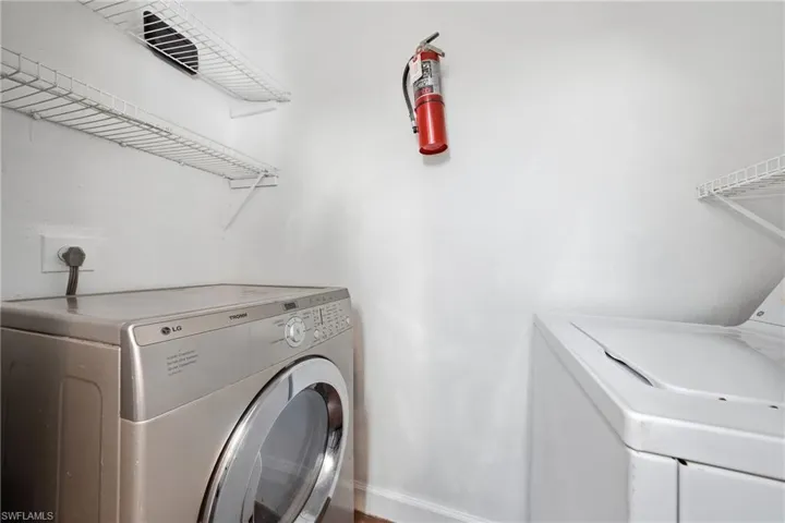 Dedicated laundry area featuring white wire shelving units and wood-finish flooring