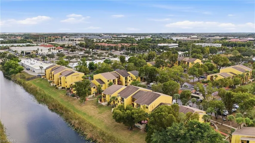 Residential buildings featuring yellow exteriors and brown roofs, bordered by a canal with green banks