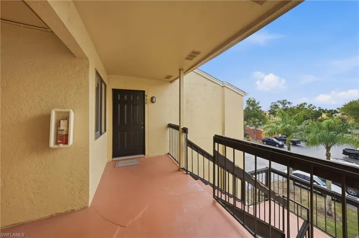 Exterior entryway featuring a dark paneled door with sidelight, textured stucco walls, and a warm-toned concrete floor