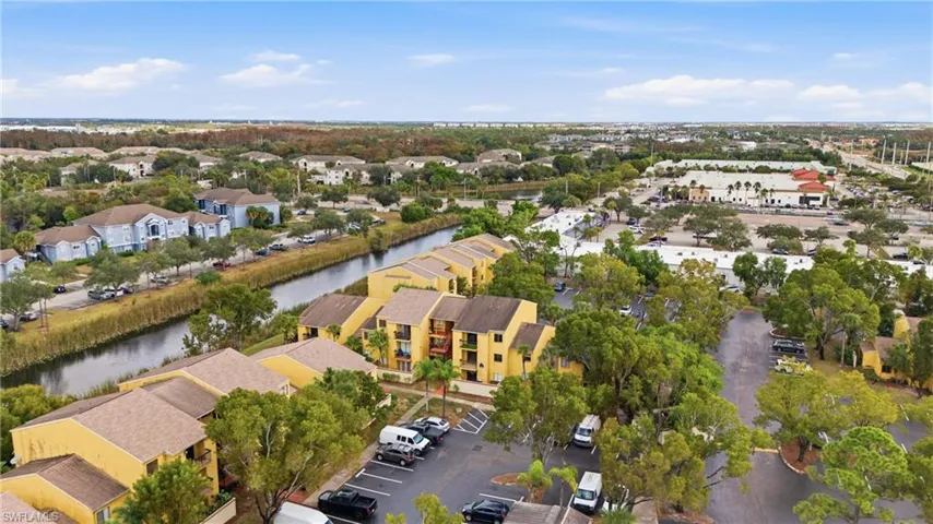 Aerial perspective showcasing a community with multi-story buildings, mature trees, and a waterway