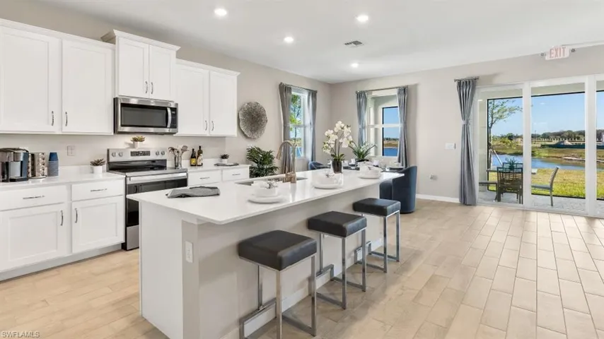 Contemporary kitchen with an island featuring white cabinetry, stainless steel appliances, and light-toned tile flooring