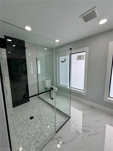 Bathroom featuring a shower with shower door and toilet