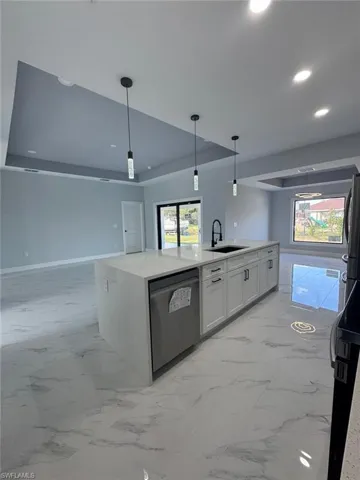 Kitchen with sink, dishwasher, white cabinets, a center island with sink, and decorative light fixtures