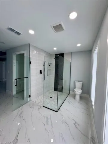 Bathroom featuring toilet and a shower with shower door