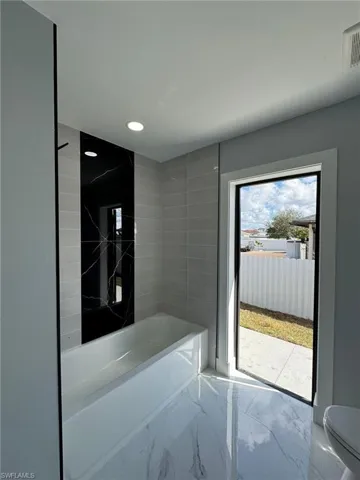 Bathroom with tiled shower / bath combo and toilet