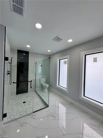 Bathroom featuring a shower with shower door and toilet
