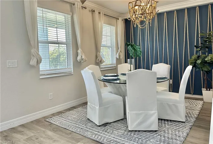 Dining space with crown molding, light wood-type flooring, and a chandelier
