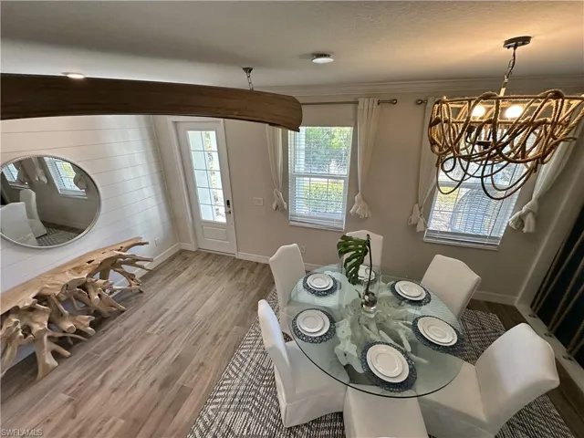 Dining space with wood finished floors, ornamental molding, and a chandelier