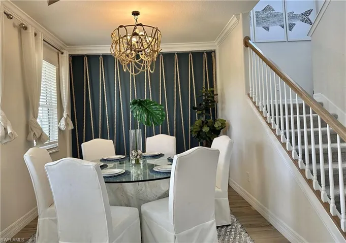 Dining room featuring wood finished floors, a chandelier, and ornamental molding
