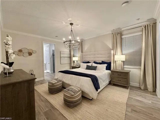 Bedroom with crown molding, wood finished floors, and a chandelier