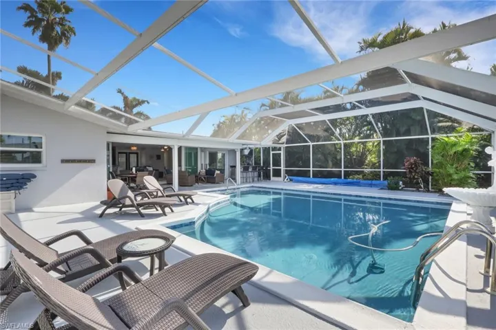 Swimming pool with glass enclosure, a patio area, and a sunroom