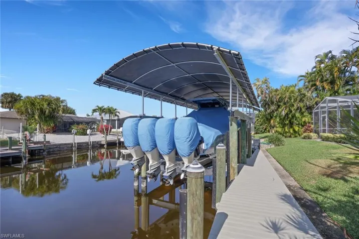Dock with boat lift, a water view, and a lanai