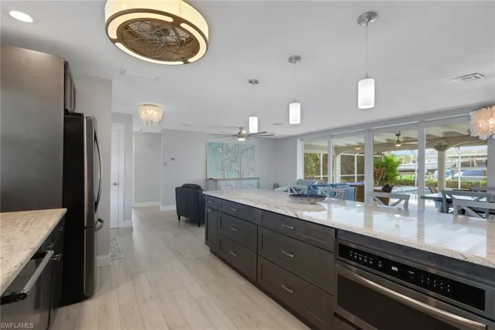 Kitchen featuring a chandelier, decorative light fixtures, light stone counters, and appliances with stainless steel finishes