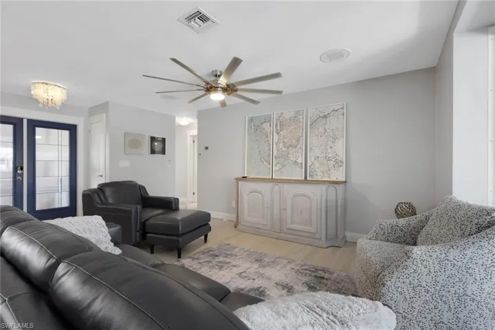 Living room with ceiling fan, light wood-type flooring, french doors, and a chandelier