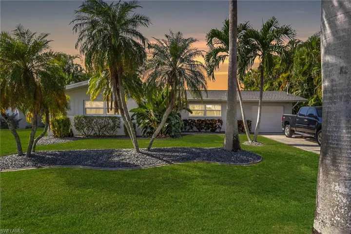 View of front of home featuring an attached garage, driveway, and a front yard