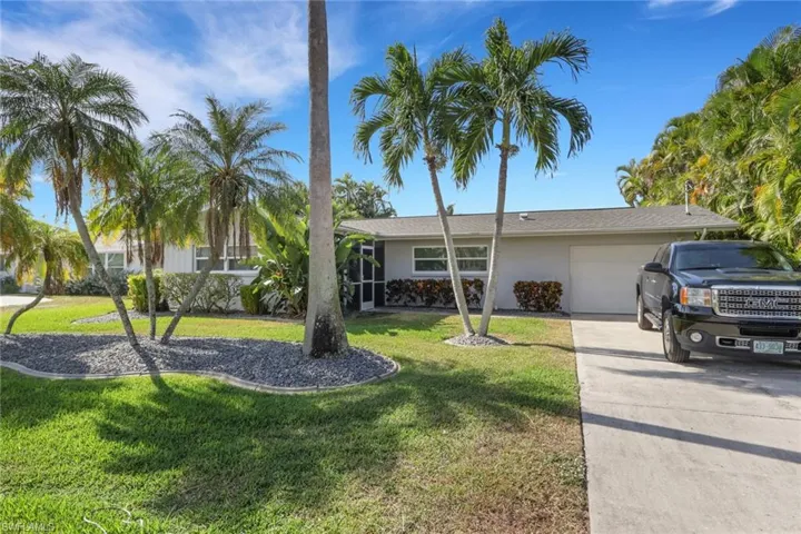 View of front of house with a garage, a front lawn, concrete driveway, and a sunroom