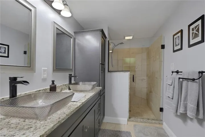Full bathroom featuring a stall shower, double vanity, and light tile patterned floors