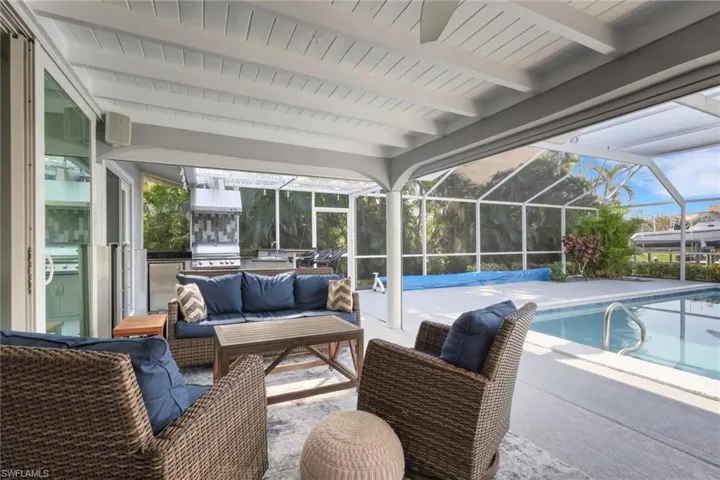 Outdoor pool with a lanai, a sunroom, a patio, outdoor lounge area, and exterior kitchen