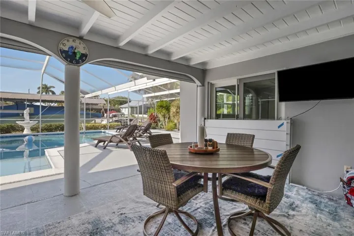 View of patio featuring a sunroom, glass enclosure, an outdoor pool, and outdoor dining area