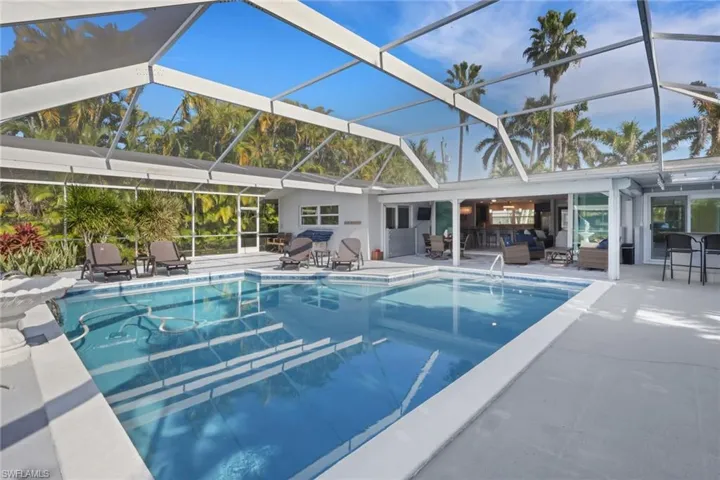 Swimming pool with a sunroom, a patio, glass enclosure, and an outdoor hangout area