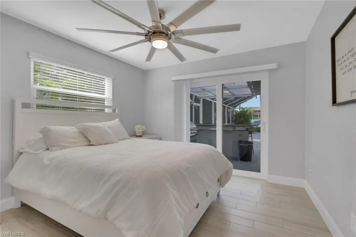 Bedroom featuring multiple windows, access to exterior, light wood finished floors, and a sunroom