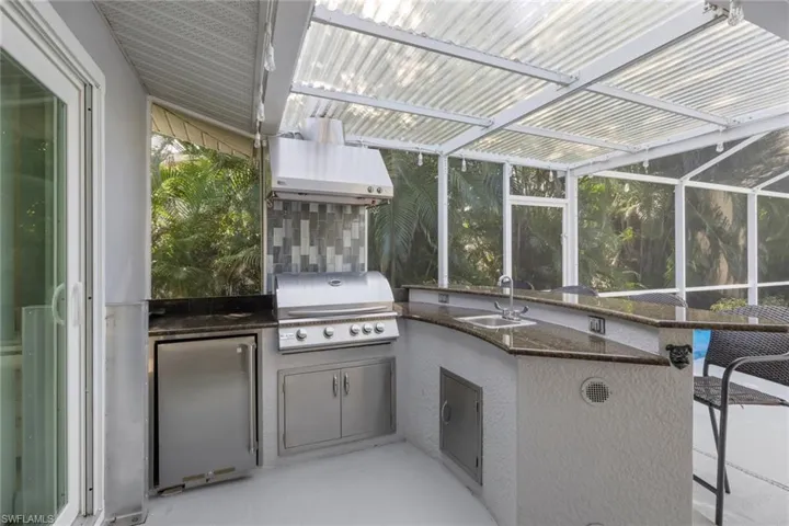 View of patio / terrace with glass enclosure, an outdoor kitchen, and a sunroom