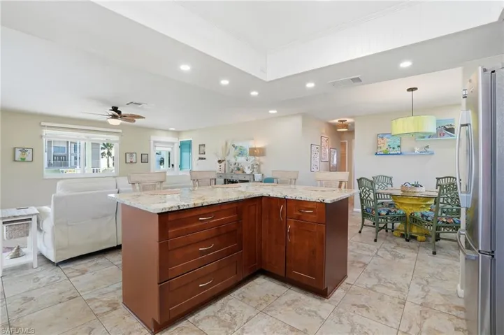 Kitchen with recessed lighting, freestanding refrigerator, open floor plan, a kitchen island, and hanging light fixtures - Virtually Edited Image
