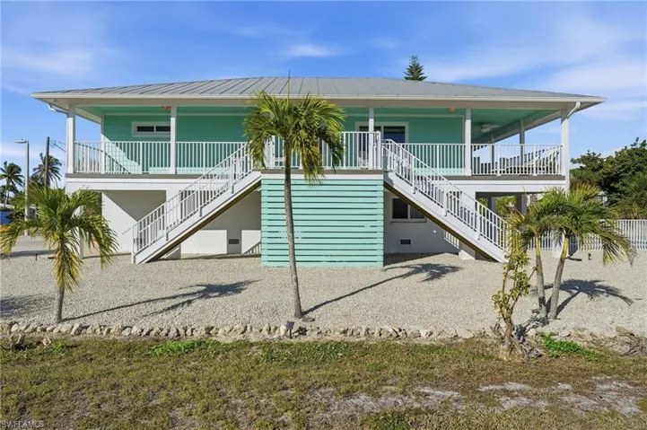 View of front of home featuring stairway, a porch, and a metal roof - Virtually Edited Image
