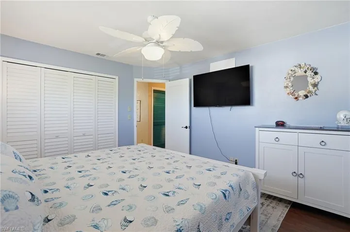 Bedroom featuring ceiling fan, a closet, and dark wood-style flooring - Virtually Edited Image