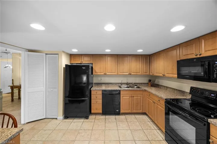 Kitchen with black appliances, recessed lighting, and brown cabinets