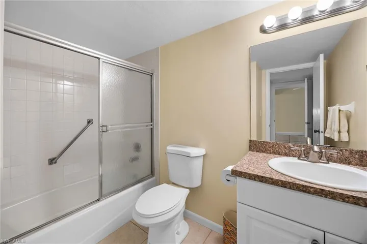 Bathroom with vanity, light tile patterned floors, and enclosed tub / shower combo