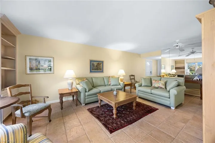 Living area featuring a ceiling fan, light tile patterned floors, and built in shelves