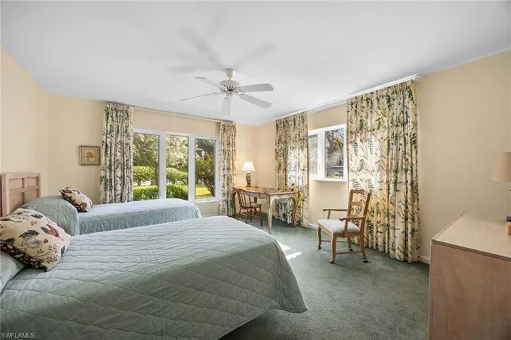 Carpeted bedroom with a ceiling fan and baseboards
