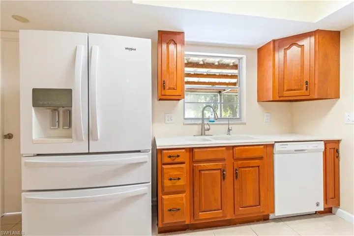 Kitchen with sink, light tile patterned floors, and white appliances