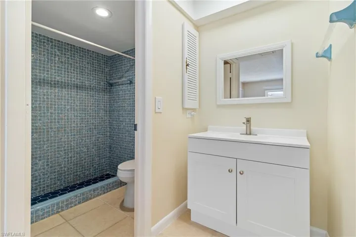 Bathroom with vanity, toilet, a tile shower, and tile patterned floors
