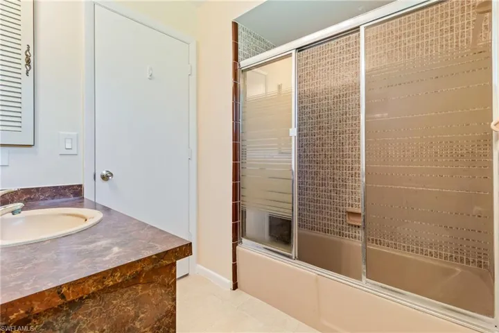 Bathroom featuring vanity, bath / shower combo with glass door, and tile patterned floors