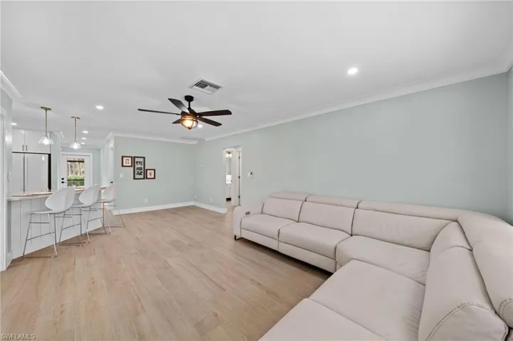 Living room featuring ceiling fan, ornamental molding, and light hardwood / wood-style flooring