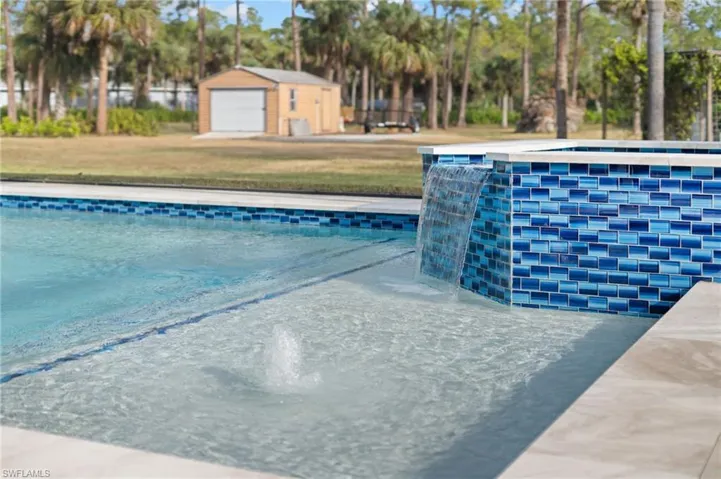 View of swimming pool with pool water feature and an outdoor structure