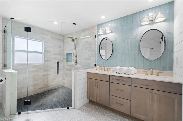 Bathroom featuring tile patterned flooring, vanity, an enclosed shower, and tile walls