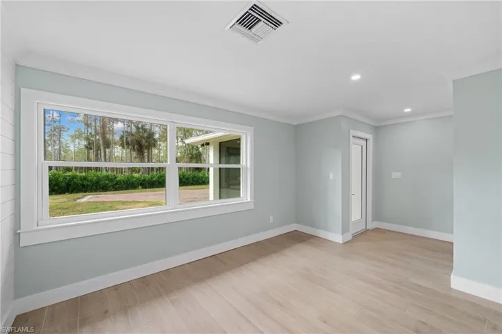 Empty room featuring crown molding and light wood-type flooring